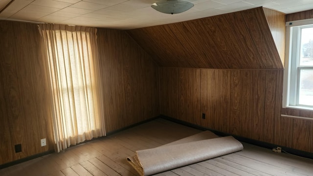 bonus room featuring light hardwood / wood-style flooring, wooden walls, and vaulted ceiling