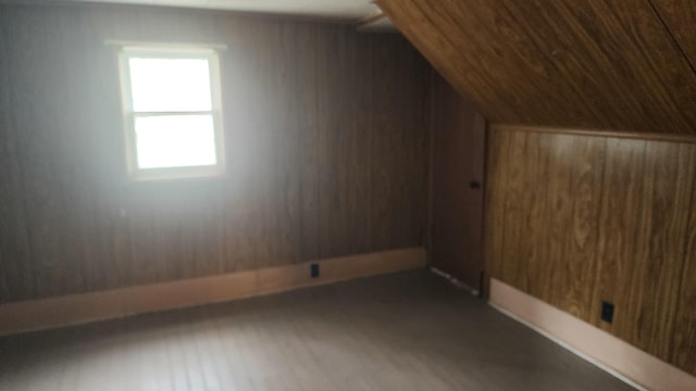 bonus room featuring lofted ceiling and wood walls