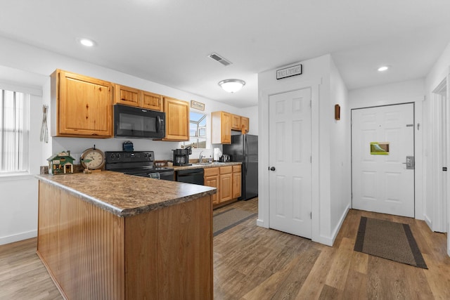 kitchen featuring sink, kitchen peninsula, light wood-type flooring, and black appliances