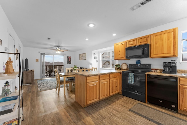 kitchen with hardwood / wood-style floors, black appliances, ceiling fan, kitchen peninsula, and light stone countertops