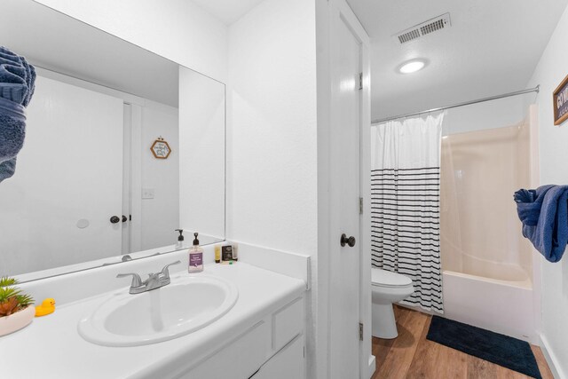 full bathroom featuring shower / tub combo with curtain, hardwood / wood-style floors, vanity, and toilet