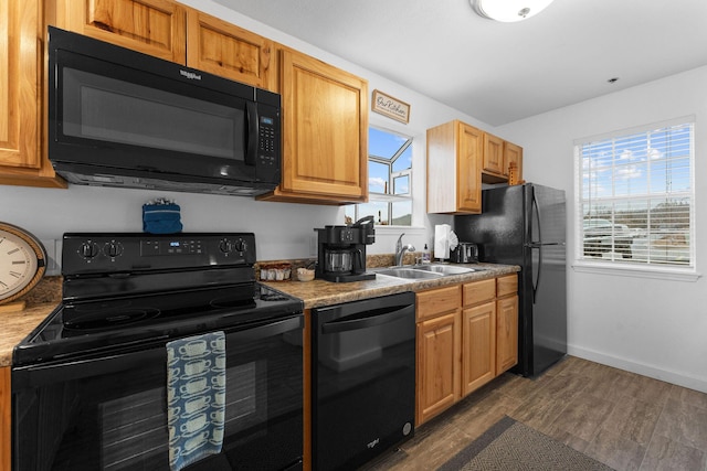 kitchen with a healthy amount of sunlight, dark hardwood / wood-style flooring, sink, and black appliances