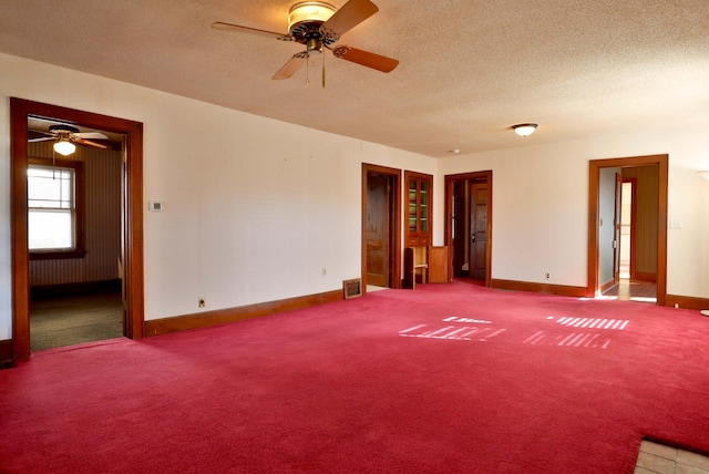 carpeted empty room featuring a textured ceiling, visible vents, and baseboards