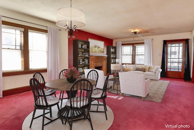 carpeted dining room featuring a fireplace, a chandelier, and a textured ceiling