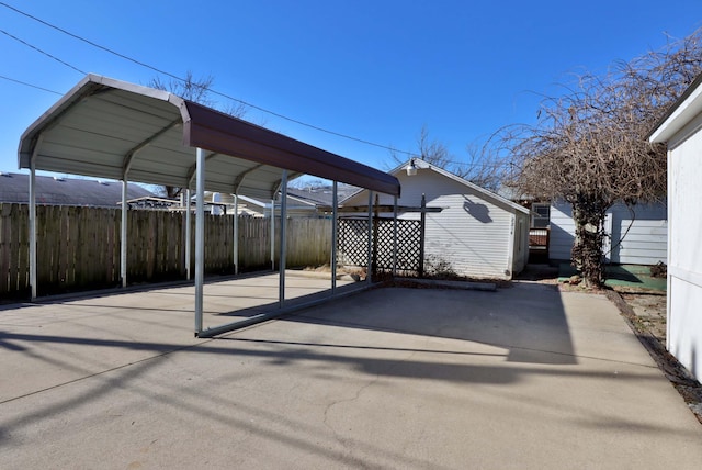 view of vehicle parking featuring fence and a carport