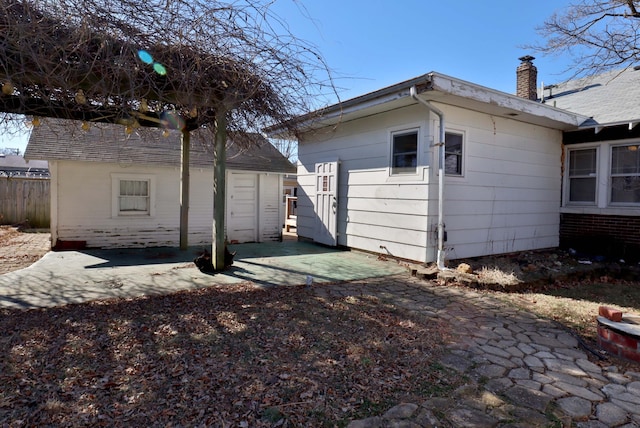 rear view of property with a patio, a chimney, and fence