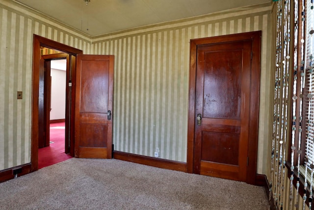 unfurnished bedroom with wallpapered walls, carpet, and baseboards