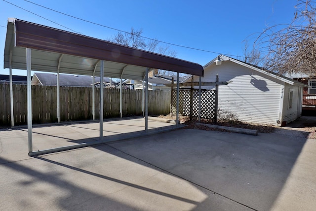 view of vehicle parking with fence and a carport