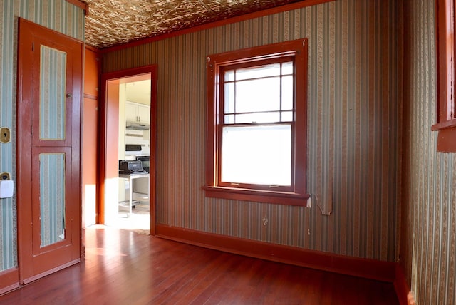 spare room with hardwood / wood-style flooring, an ornate ceiling, baseboards, and wallpapered walls