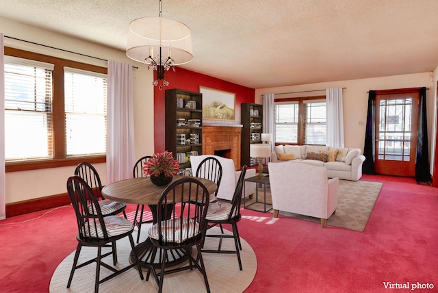 dining space featuring a chandelier, a textured ceiling, a fireplace, and carpet flooring