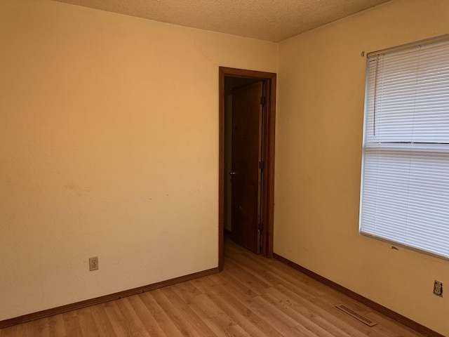 spare room with light hardwood / wood-style floors and a textured ceiling