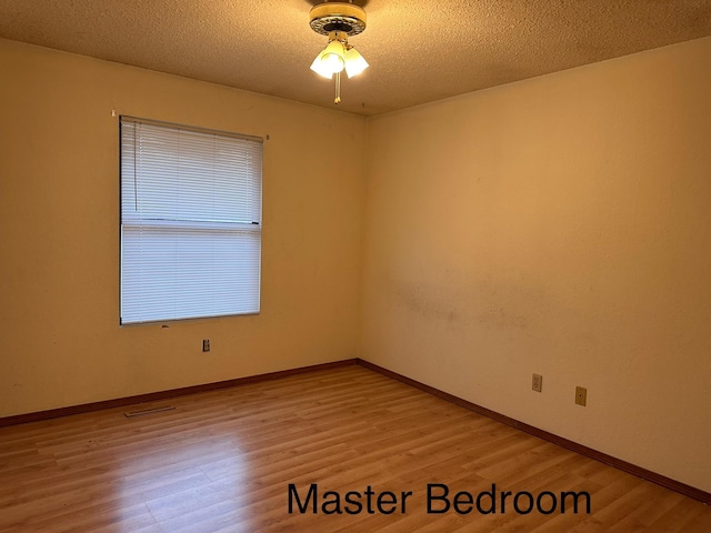 spare room featuring ceiling fan, light hardwood / wood-style flooring, and a textured ceiling