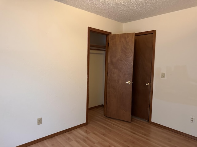 unfurnished bedroom with a closet, a textured ceiling, and light hardwood / wood-style flooring