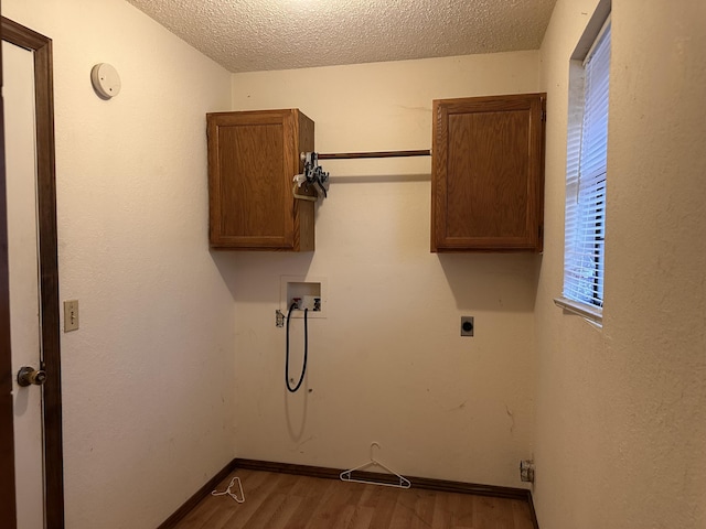 laundry room with electric dryer hookup, hardwood / wood-style floors, hookup for a washing machine, cabinets, and a textured ceiling