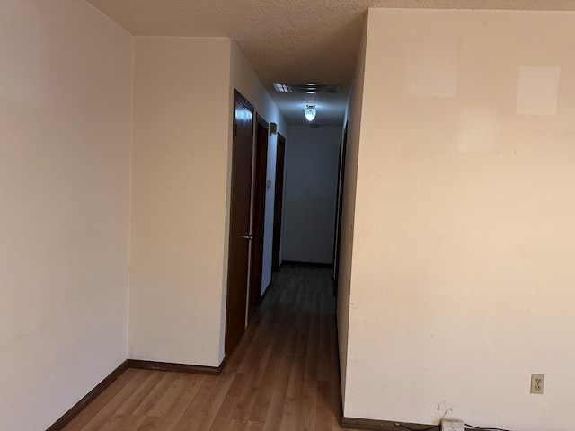 hall with hardwood / wood-style floors and a textured ceiling