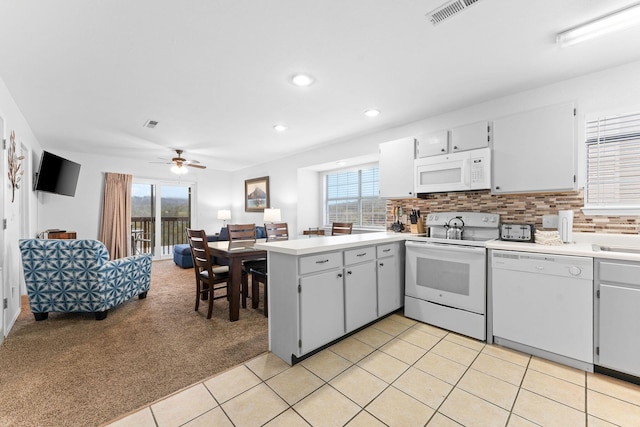 kitchen featuring light carpet, backsplash, white appliances, and kitchen peninsula