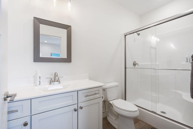 bathroom with walk in shower, vanity, toilet, and hardwood / wood-style floors