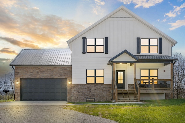 modern farmhouse with a garage, covered porch, and a lawn