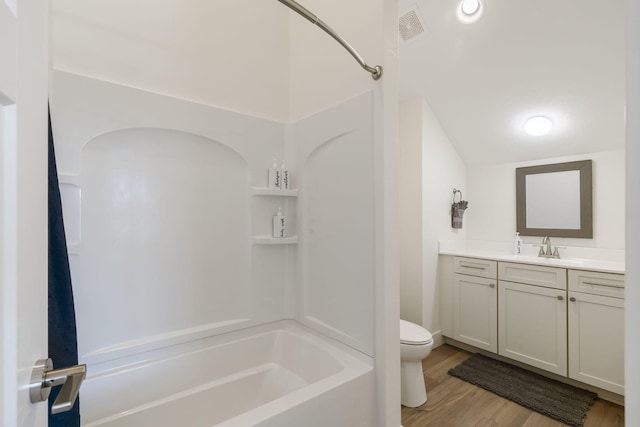 full bathroom with vaulted ceiling, hardwood / wood-style floors, bathtub / shower combination, vanity, and toilet