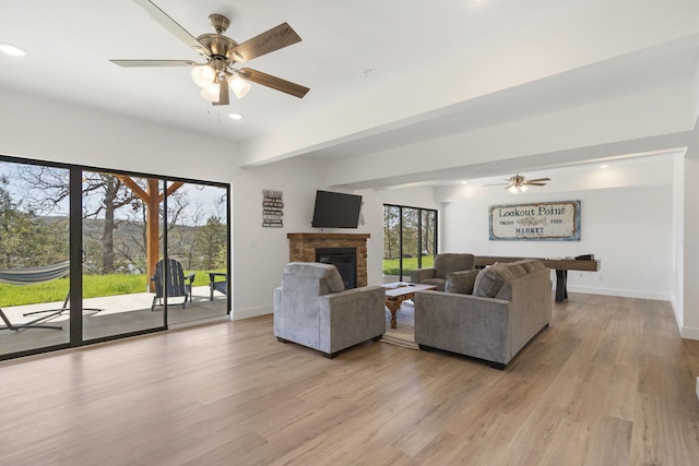 living room featuring beamed ceiling, ceiling fan, and light wood-type flooring