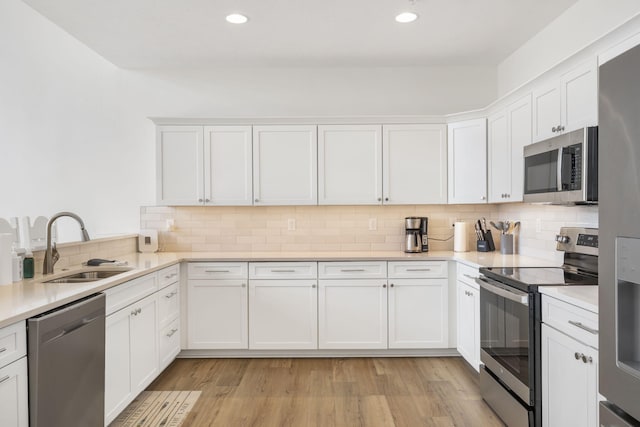 kitchen with sink, backsplash, white cabinets, and appliances with stainless steel finishes