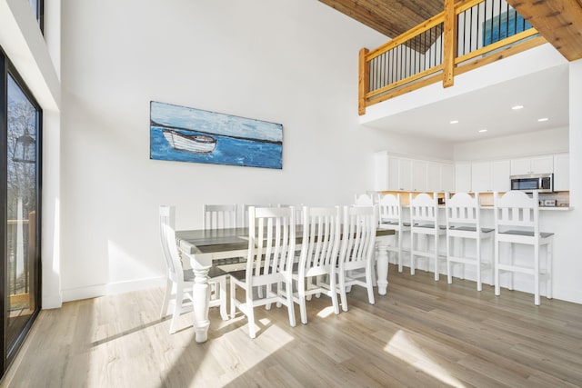 dining room with a towering ceiling and light hardwood / wood-style flooring