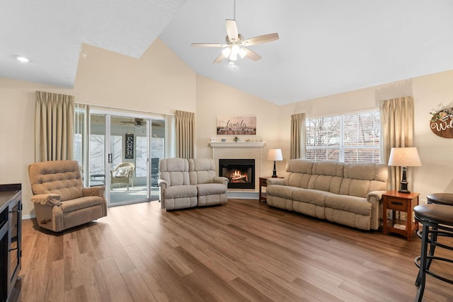 living room featuring ceiling fan, high vaulted ceiling, and light hardwood / wood-style flooring