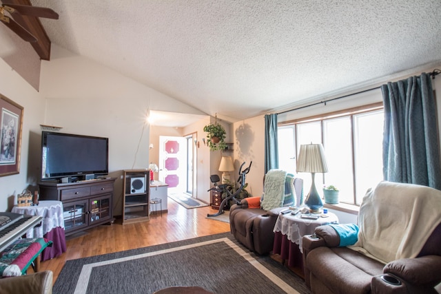 living room featuring vaulted ceiling, hardwood / wood-style floors, and a textured ceiling