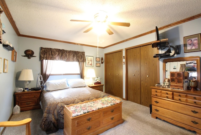 carpeted bedroom featuring crown molding, ceiling fan, a textured ceiling, and two closets