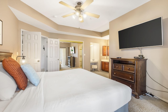 bedroom featuring ceiling fan, light colored carpet, a closet, and ensuite bath