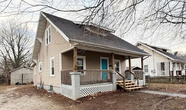 bungalow-style house with a storage unit and a porch