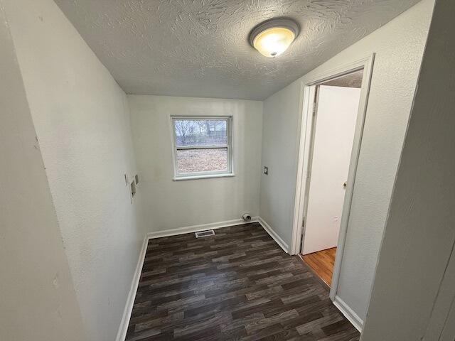 laundry room with dark hardwood / wood-style floors and a textured ceiling