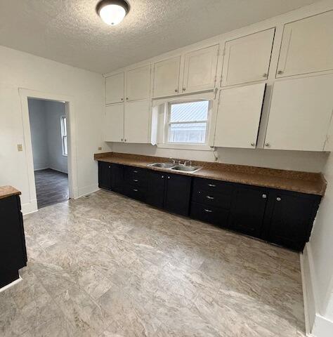 kitchen with white cabinetry, sink, and a textured ceiling