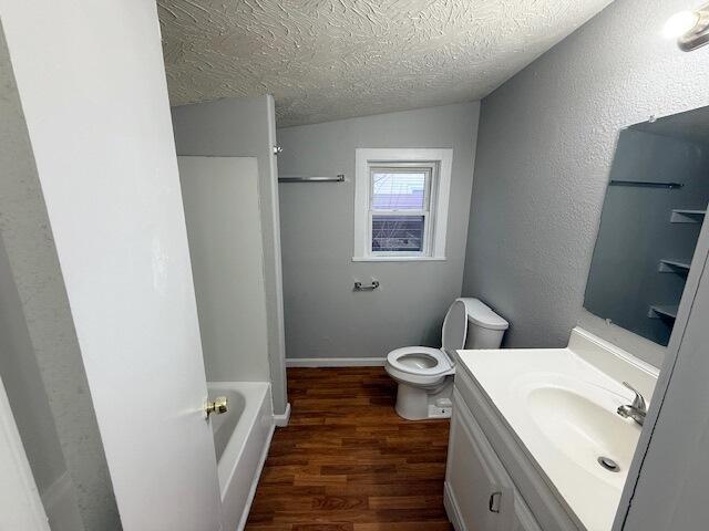 bathroom featuring a washtub, hardwood / wood-style floors, vanity, a textured ceiling, and toilet