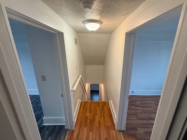 hall with hardwood / wood-style flooring and a textured ceiling