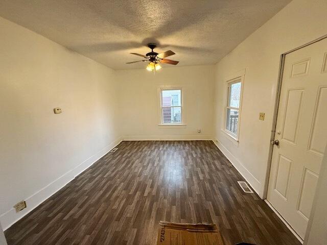 unfurnished room featuring ceiling fan, dark wood-type flooring, and a textured ceiling