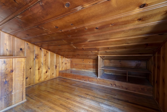 bonus room with vaulted ceiling, wooden ceiling, light wood-type flooring, and wood walls