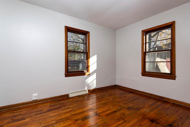 unfurnished room featuring plenty of natural light, dark hardwood / wood-style floors, and baseboard heating