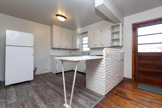 kitchen with white cabinetry, backsplash, a kitchen breakfast bar, dark hardwood / wood-style floors, and white refrigerator