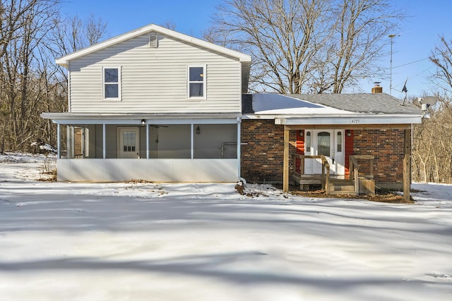 snow covered house featuring a sunroom