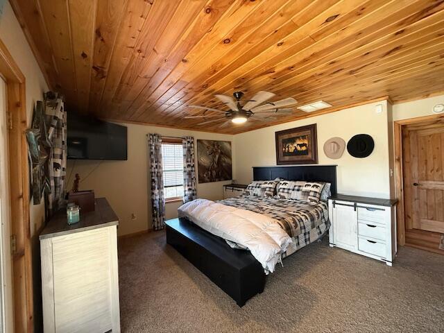 bedroom with ceiling fan, dark carpet, and wooden ceiling