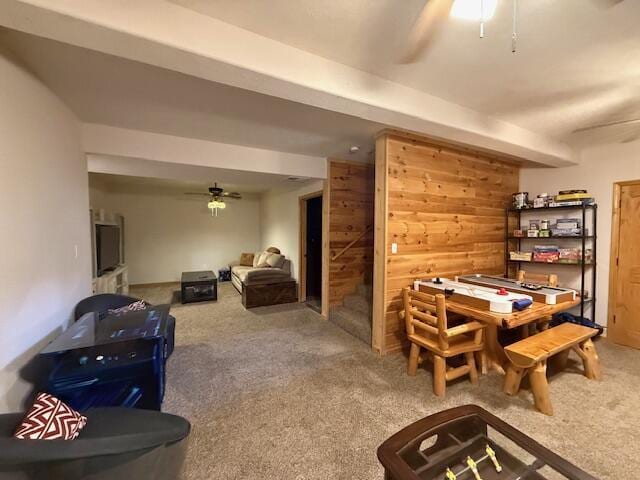 interior space with carpet flooring, ceiling fan, and wood walls