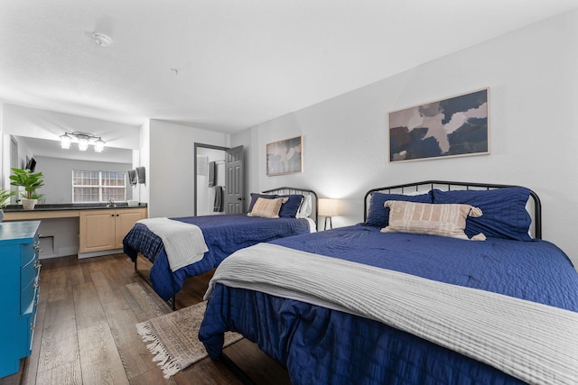 bedroom featuring built in desk and dark hardwood / wood-style flooring