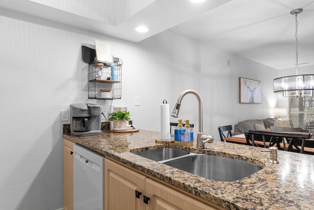 kitchen with white dishwasher, sink, light brown cabinetry, and dark stone countertops