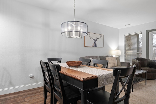 dining area with wood-type flooring and a chandelier