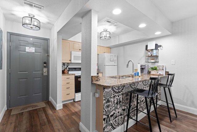 kitchen with dark hardwood / wood-style floors, white appliances, light brown cabinetry, and kitchen peninsula