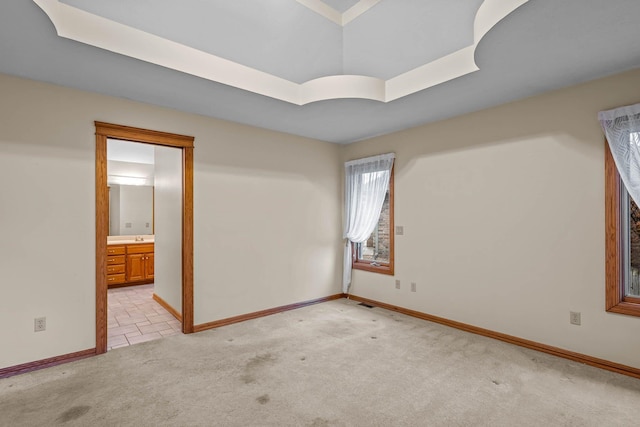 empty room featuring light colored carpet and a tray ceiling