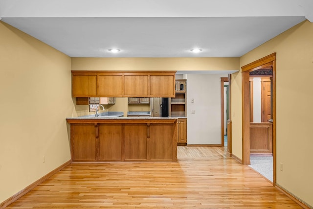 kitchen with a kitchen breakfast bar, light wood-type flooring, stainless steel refrigerator, and kitchen peninsula