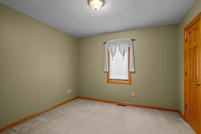 carpeted empty room featuring a textured ceiling