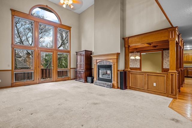 unfurnished living room featuring light colored carpet, a brick fireplace, and a high ceiling